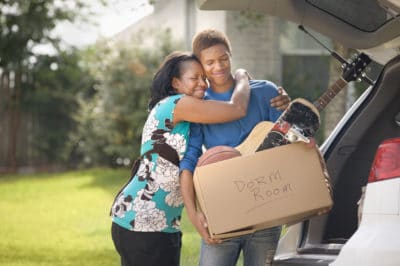 Mother hugging teenage son as he packs for college