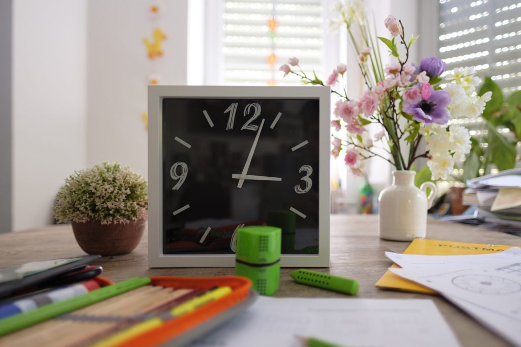 Clock and school supplies on desk