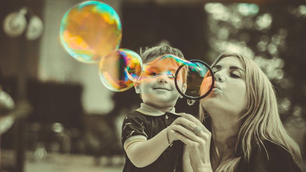 mom and son blowing bubbles together outside