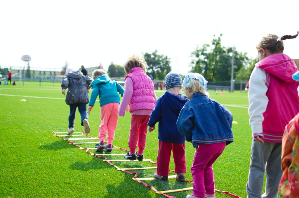 Kids lined up and standing in rings on a grassy field