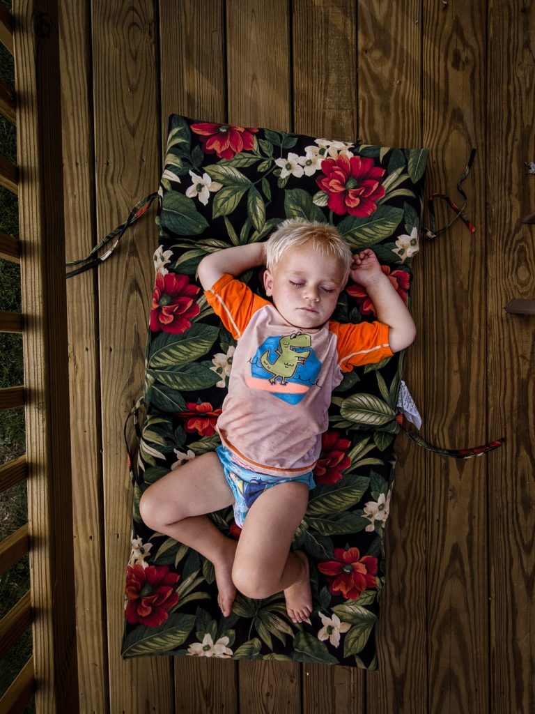 Blond boy laying on a mat, sleeping