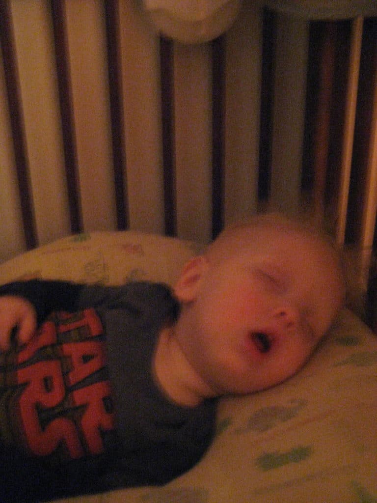 blond boy snoring with mouth open in crib