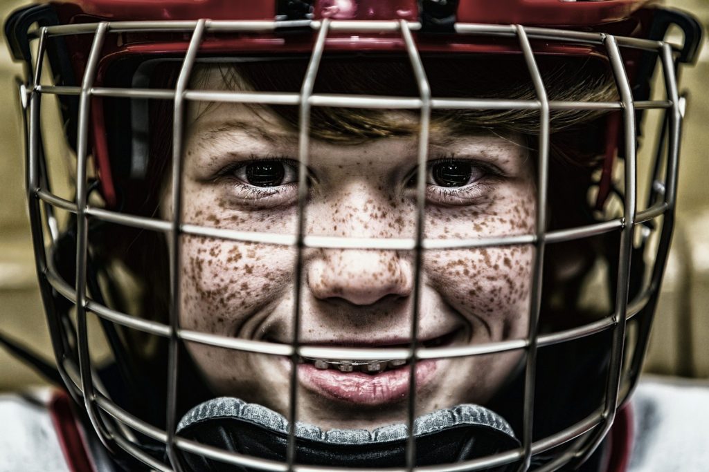 Freckled boy w braces on his teeth, wearing football helmet