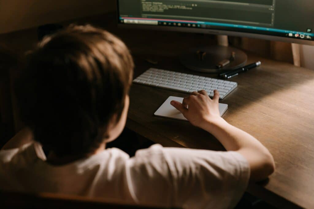 Boy in White T-shirt Sitting on Chair in Front of Computer