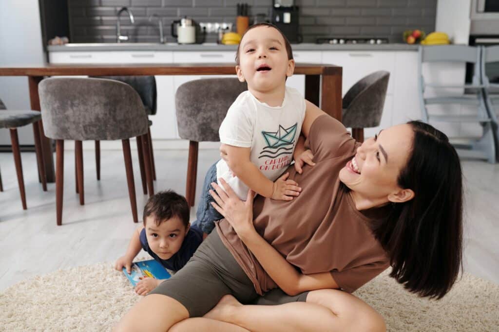 smiling woman playing with two young male children