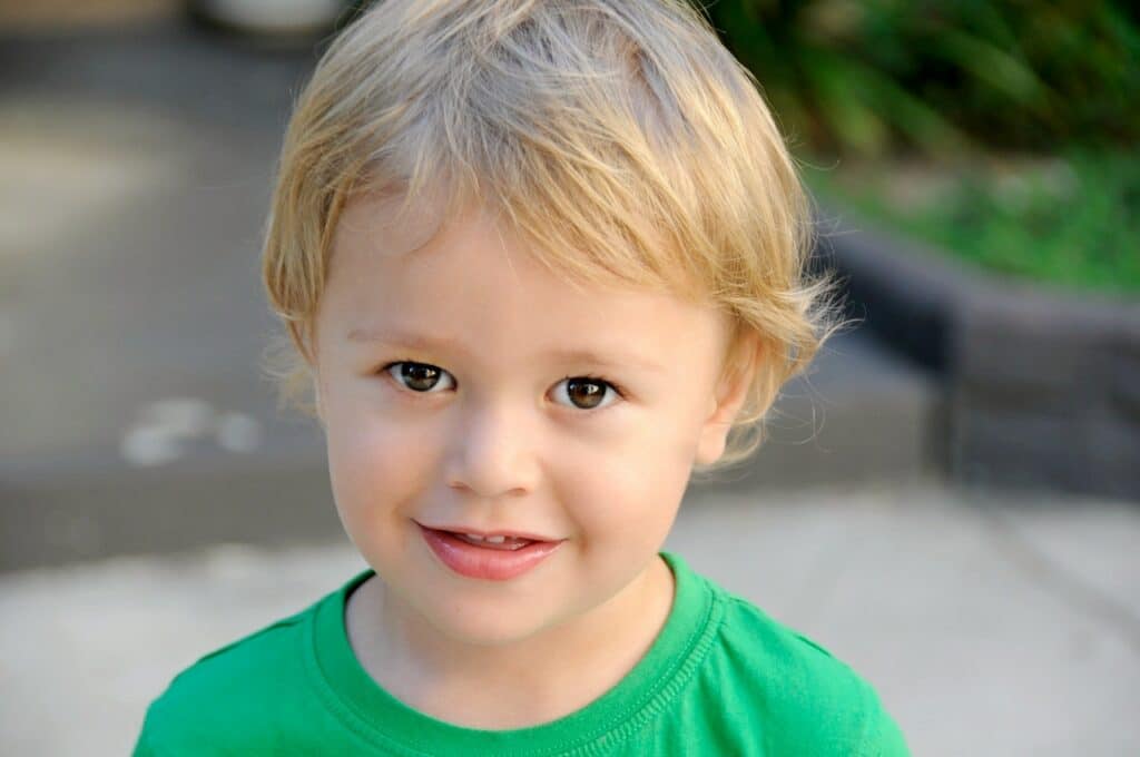 smiling young boys with blond hair wearing green crew neck tee shirt