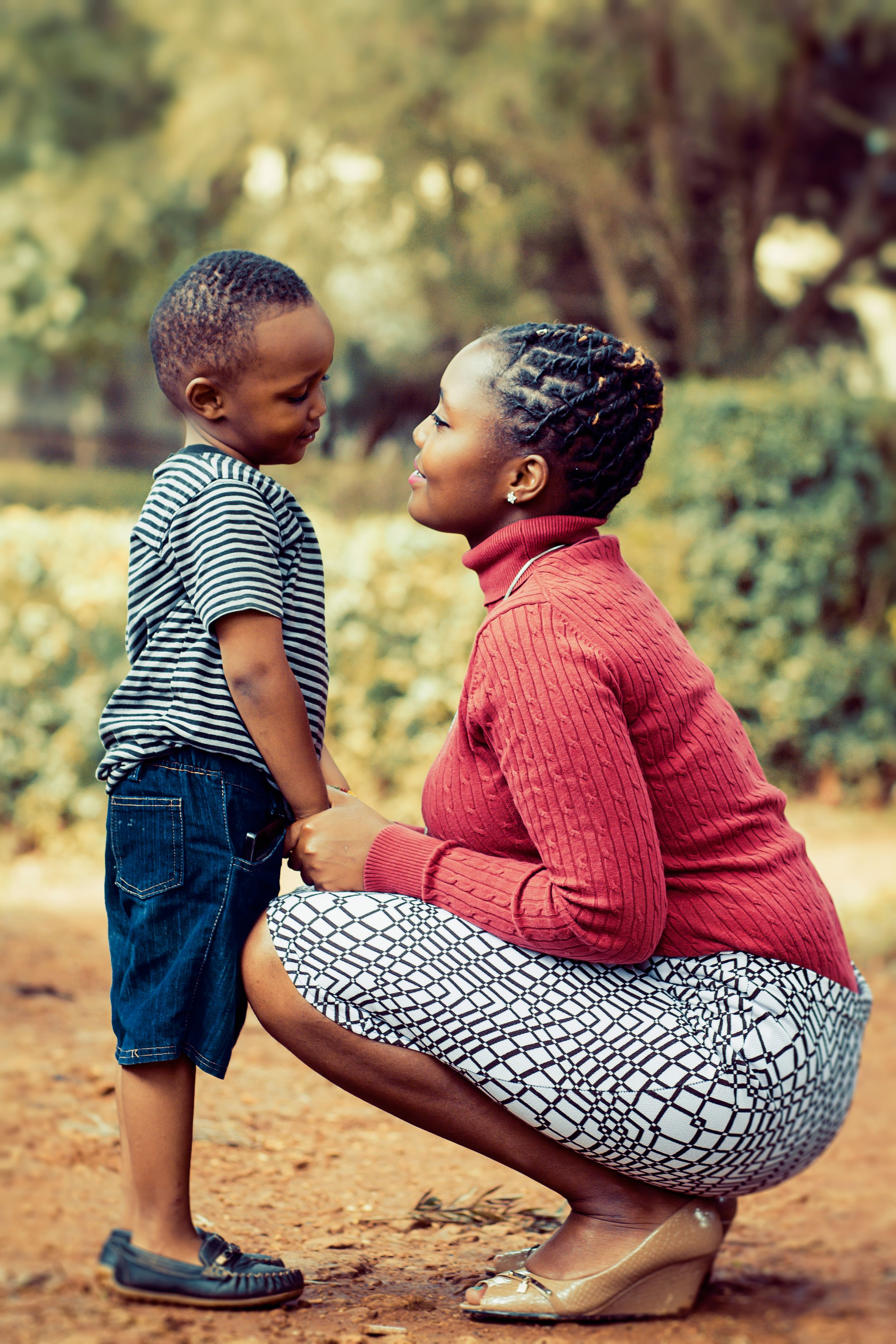 Young black boy stands in front of his mom