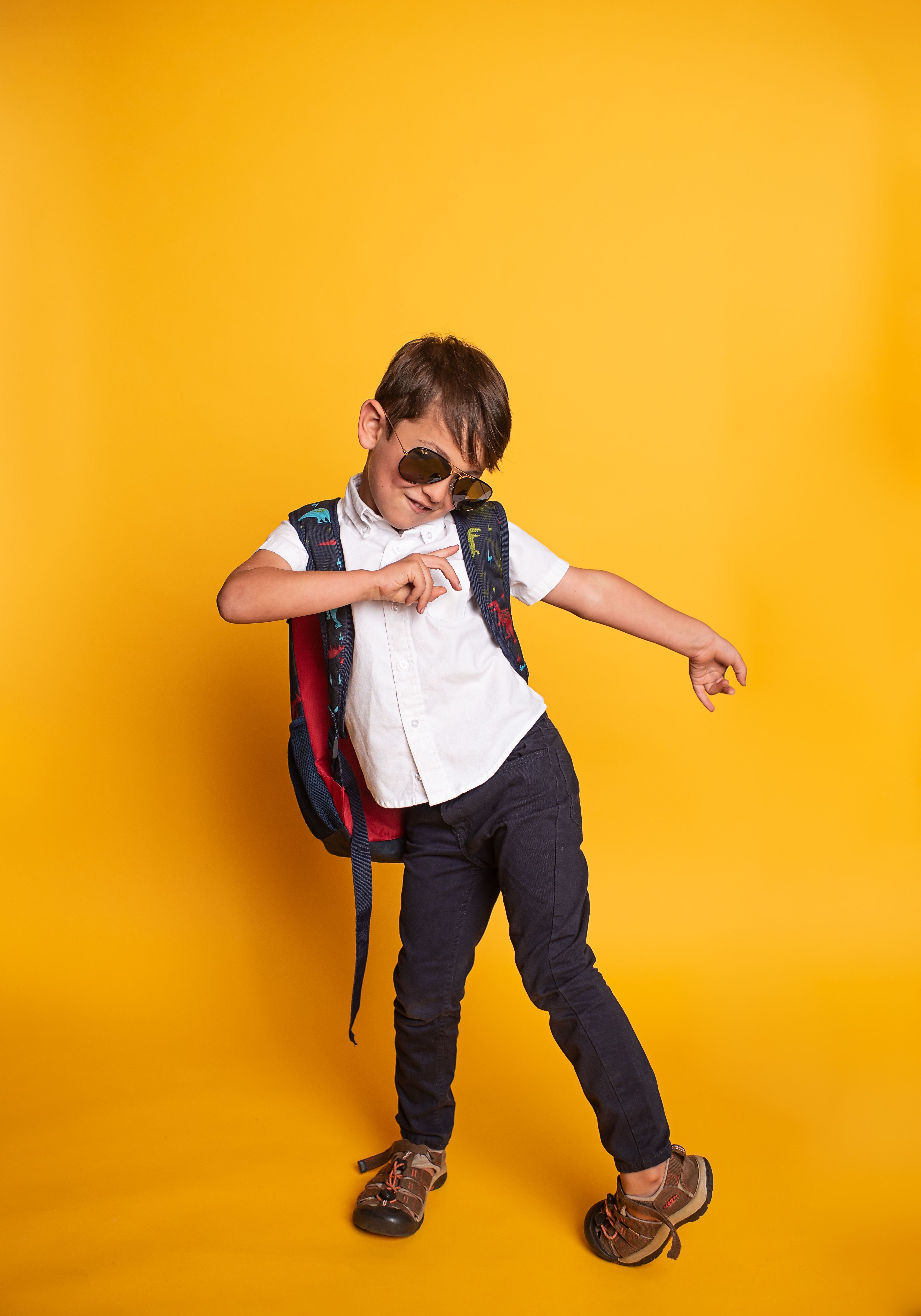 School-aged boy wearing sunglasses and a backpack